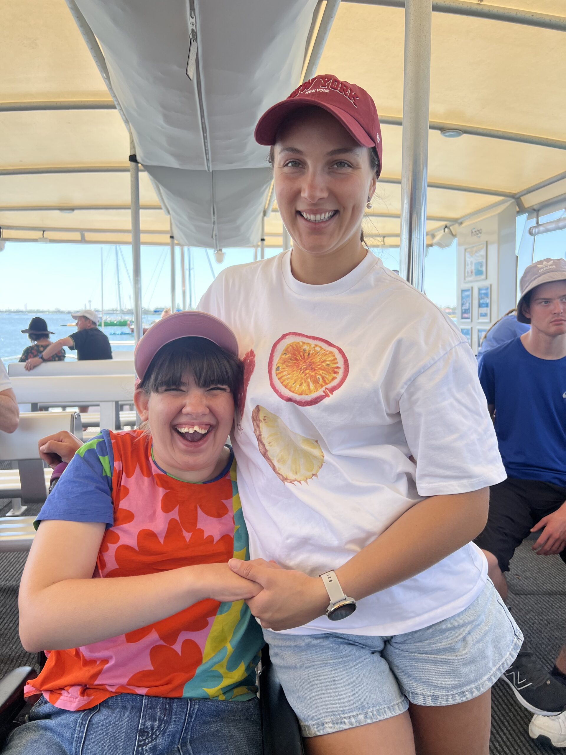 A participant and support worker smiling together on a boat trip